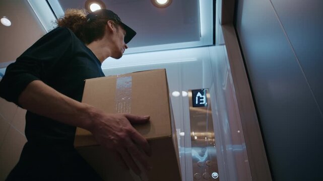 Delivery worker holding a parcel riding a modern elevator in a residential building