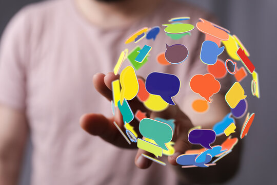 Creative image of a person holding a globe made of speech bubbles, representing global communication, social media, and online interaction. Idea