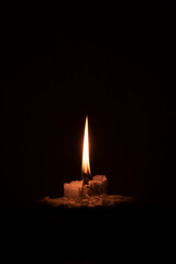 Close up of a burning candle in the darkness. Christmas and prayer concept. Vertical image. For...