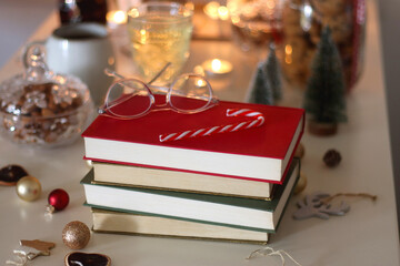 Cookie jar, tea, wine, nuts, books, lit candles and Christmas decorations on the table. Cozy Christmas hygge at home. Selective focus.