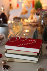 Cookie jar, tea, wine, nuts, books, lit candles and Christmas decorations on the table. Cozy Christmas hygge at home. Selective focus.