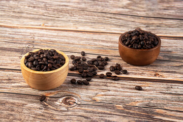 Coffee beans in a wooden cup against a wooden table background.