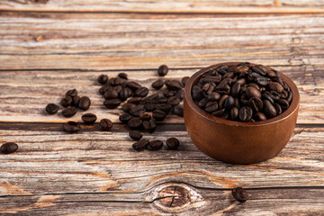 Coffee beans in a wooden cup against a wooden table background.