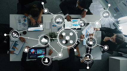 A top-down view of a business meeting showcasing professionals discussing strategies with digital connectivity elements and data visualization to enhance collaboration. Amity