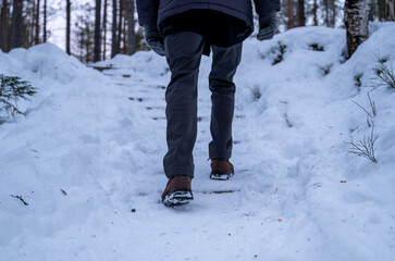 man hiking on snowy winter trail with snow covered boots in lapland