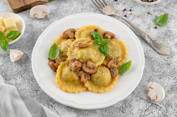 Tradition homemade Italian ravioli pasta with ricotta, mushrooms and parmesan cheese in a white plate on a concrete background. Top view.