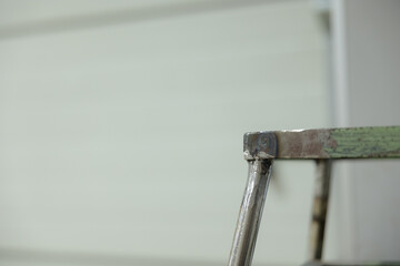 Rustic metal step ladder leaning against a white wall in a cozy workshop space