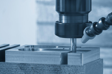 The CNC milling machine cutting  aluminum part by solid flat nose end mill tool in the light blue scene.