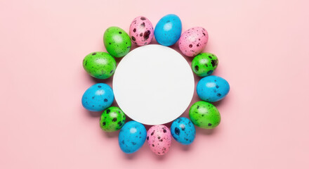 Colorful speckled easter eggs in circle around blank white paper card on pastel pink background for festive spring celebration