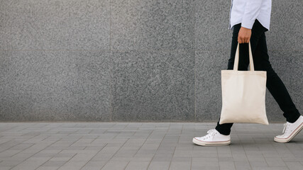 Walking with a tote bag along the city pavement
