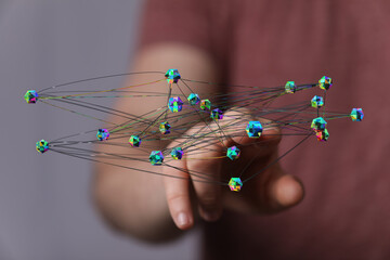 Abstract network of interconnected nodes held by a person. Represents concepts like technology, communication,