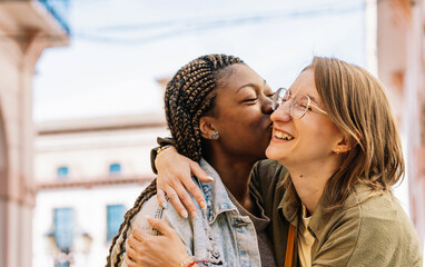Happy multiracial lesbian couple kissing on cheek outdoors