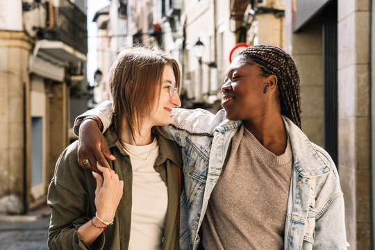 Interracial lesbian couple embracing walking on city street