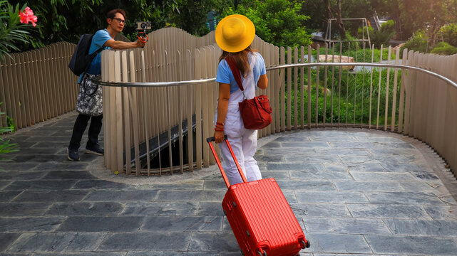 Asain couple Vlogger Filming a Traveler on the Path garden in the city