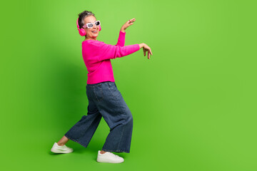 Energetic mature lady dancing in pink sweater with headphones green background perfect for lifestyle fashion wellness and advertising stock