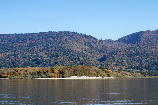 Mountain lake with gentle ripples, autumn forested hills and distant ridges under clear blue sky - Powered by Adobe