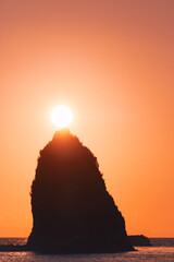 Bright sun above a large sea rock at sunset, Esashi, Hokkaido