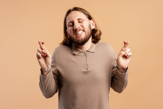 Man closing eyes and crossing fingers, wishing for good luck and success - Powered by Adobe