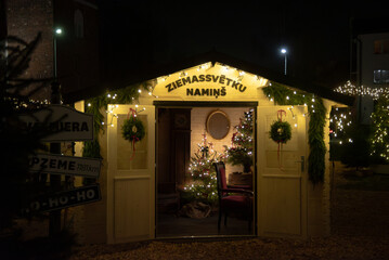 Valmiera,Latvia-November 30,2025-A cozy Christmas cabin decorated with wreaths, lights, and a...