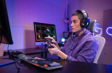 A focused gamer sits at a desk and types on a mechanical keyboard in a neon-lit gaming setup © Wosunan