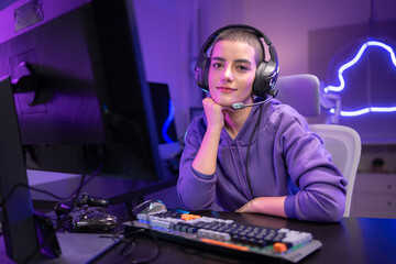 A focused gamer sits at a desk and types on a mechanical keyboard in a neon-lit gaming setup © Wosunan