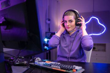 A focused gamer sits at a desk and types on a mechanical keyboard in a neon-lit gaming setup © Wosunan