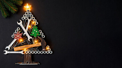 Creative Christmas tree made from mechanic's tools and hardware on black background. Text space