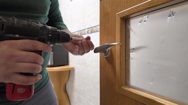 Handyman using cordless drill to fix door handle