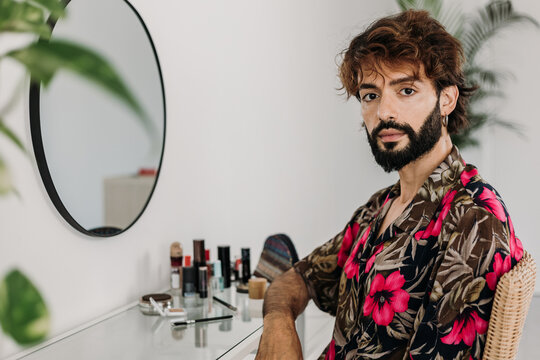 Stylish influencer applying makeup at chic vanity table, embracing self-care and grooming with confidence and modern style. LGBTQ lifestyle concept