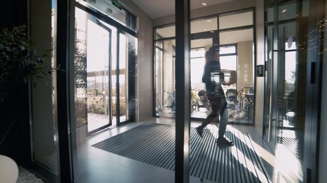 Courier enters a contemporary residential building lobby to deliver a cardboard box parcel