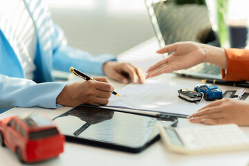 Car salesman and customer signing contract and agreement on document terms of agreement on document concept of car rental service close up.
