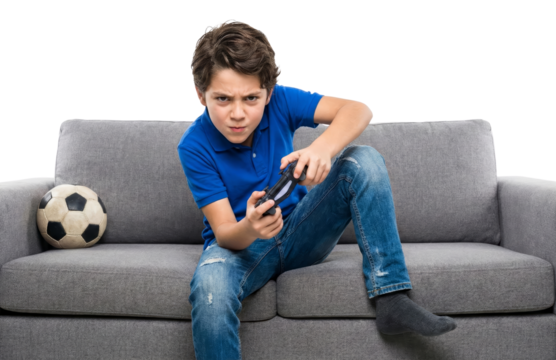 Intense young gamer absorbed in video games on sofa with isolated backdrop