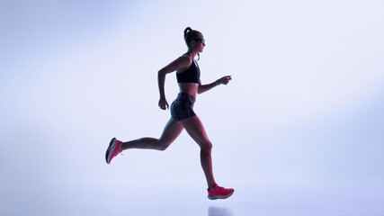 Female athlete running in neon gradient studio with modern sport aesthetics. Concept of fitness marketing, cardio training visuals, performance coaching, and dynamic sportswear promotion.