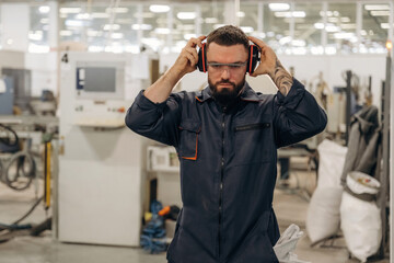In protective headphones. Warehouse worker in an industrial environment of a factory or storage area