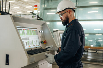 Looking at display of machine, operator is working. Warehouse worker in an industrial environment...