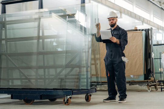 Quality control of the glass for windows. Warehouse worker in an industrial environment of a factory or storage area - Powered by Adobe
