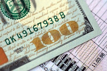 Hundred dollar bill on US driver license close up. Concept of driving lessons or automobile taxpaying