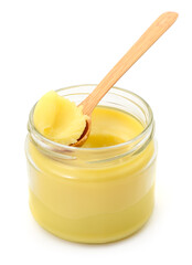 Ghee clarified butter in glass jar with wooden spoon isolated on white background