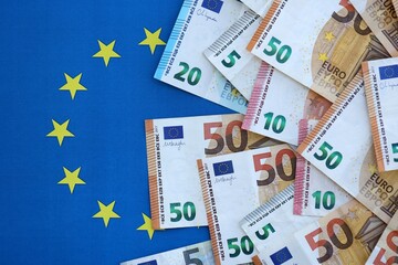 Many euro money bills banknotes on flag of European Union. Concept of business and finances in Europe