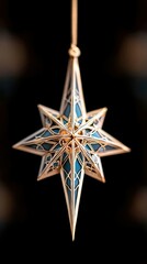 A close-up shot of an ornamental star hanging against a black background. The star is gold and teal, with intricate details. The lighting creates a festive mood