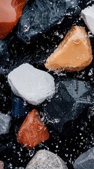 Close-up of colorful rocks partially submerged in water, creating an abstract texture with water droplets and a dark background.