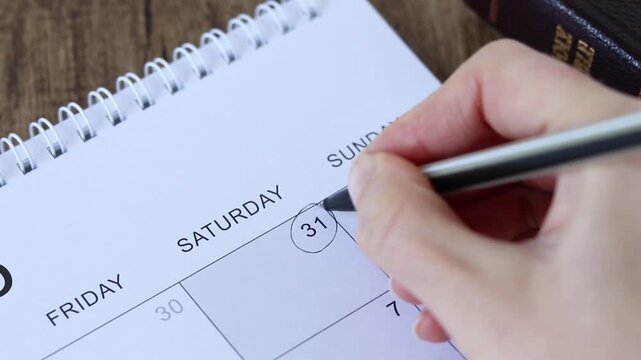 Close up of hand holding pen and marking Saturday (Christian Sabbath day) in a calendar. Biblical rest, praise and obedience to God Jesus Christ concept.