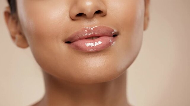 A close-up shot captures the lower face of a woman, focusing intimately on her perfectly formed, glistening lips and radiant, healthy skin. Her mouth is slightly open, revealing a hint of natural teet