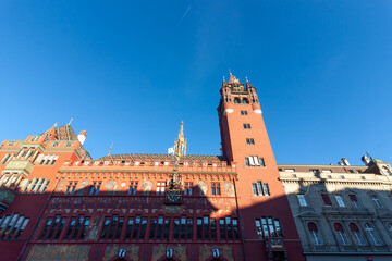 Magnificent red facade of the historic Town Hall (Rathaus) featuring the clock tower, golden spire, and colorful frescoes against a blue sky