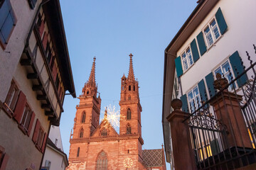 The twin towers of the historic Basel Minster cathedral (Munster) illuminated at dusk with a hanging Christmas star decoration