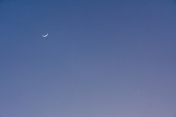 Crescent moon and Venus glowing in deep blue sky