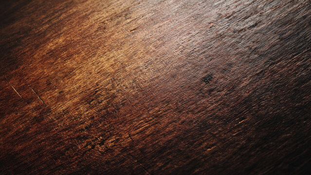 A rustic dark brown wooden surface, showcasing rich texture, natural grain patterns, and subtle scratches, beautifully illuminated by a soft, warm light.