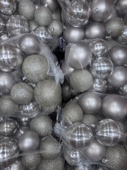 A large collection of silver Christmas ornaments in various finishes, including matte, glossy, and glitter, packaged together for holiday decorating.
