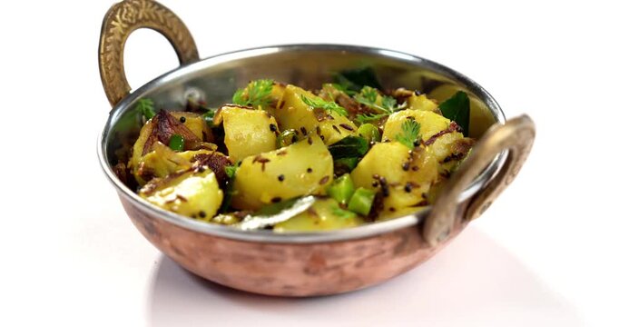 Dry Potato sabzi or Jeera Aloo fry is an Indian lunch/dinner recipe served in a plate with Roti/paratha of Indian bread over colourful/wooden background. Selective focus