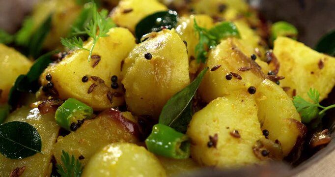 Dry Potato sabzi or Jeera Aloo fry is an Indian lunch/dinner recipe served in a plate with Roti/paratha of Indian bread over colourful/wooden background. Selective focus